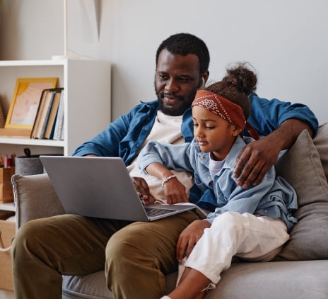 Pai e filha sentados com notebook no colo 