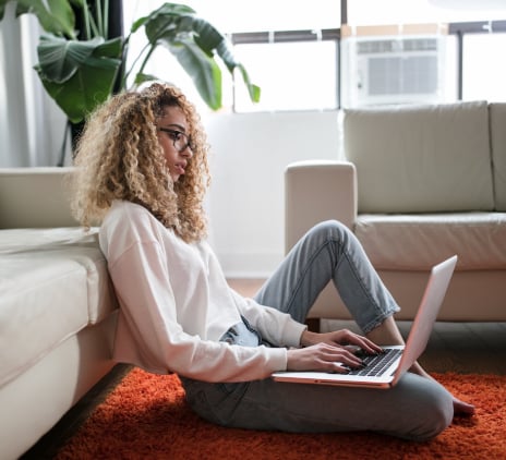 Mulher sentada no chão com notebook no colo 