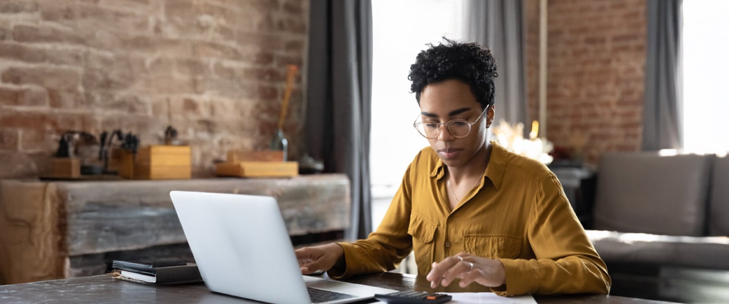 Mulher negra utilizando notebook para trabalho