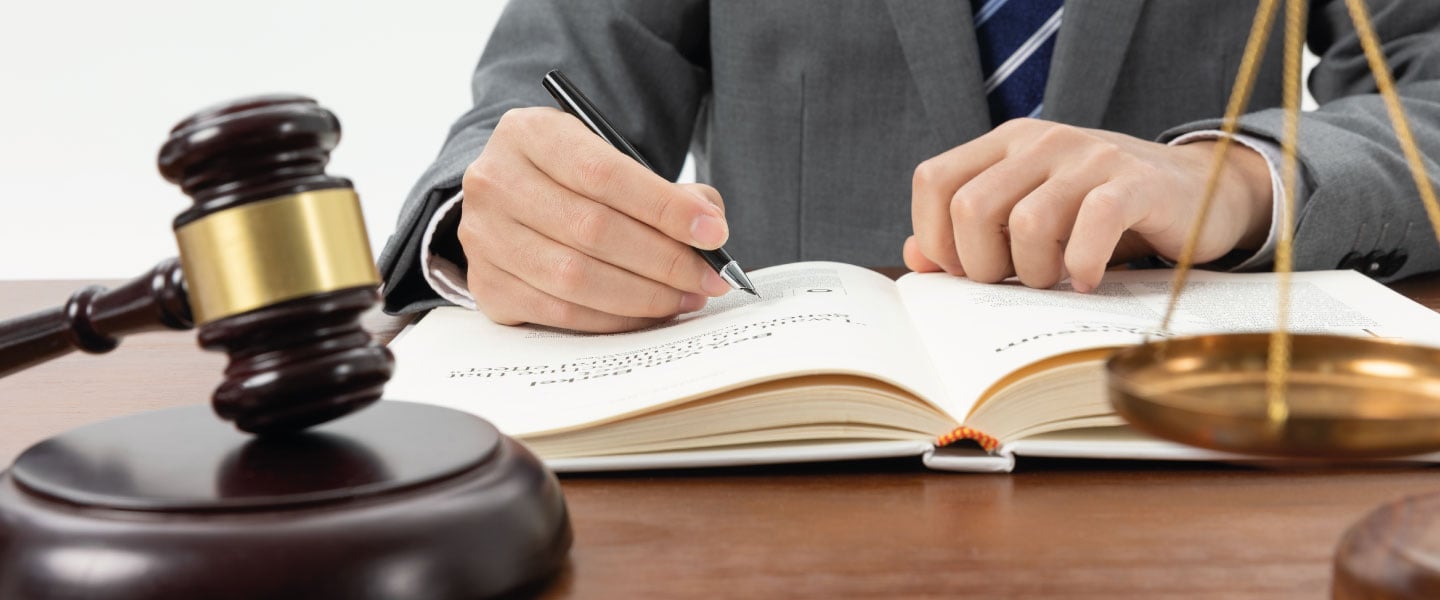 Captura aproximada de uma pessoa escrevendo em um livro com um martelo em cima da mesa