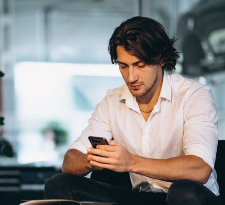 Homem branco mexendo no celular em sala branca 